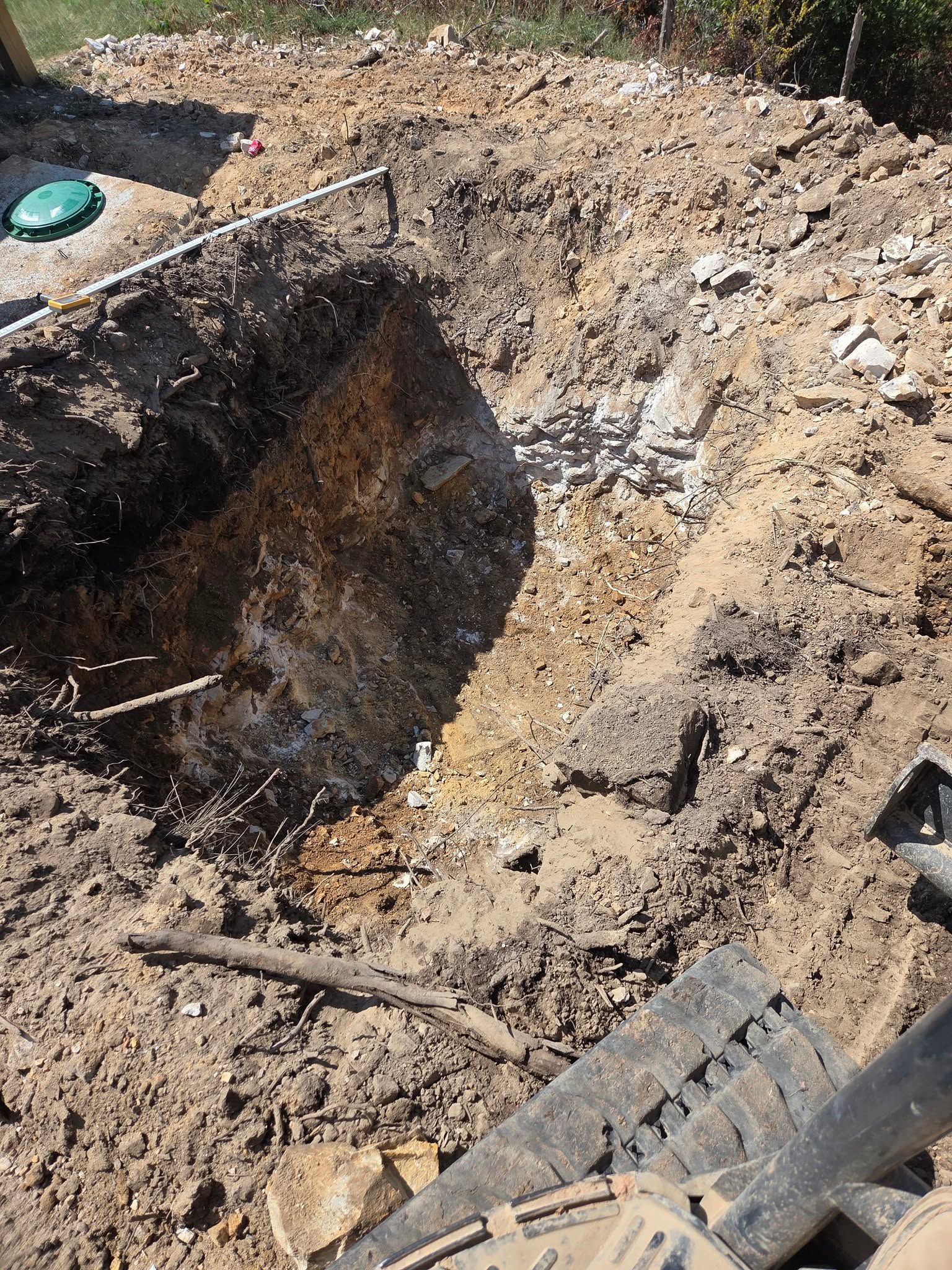 Excavated dirt pit with rough soil and debris at a construction site
