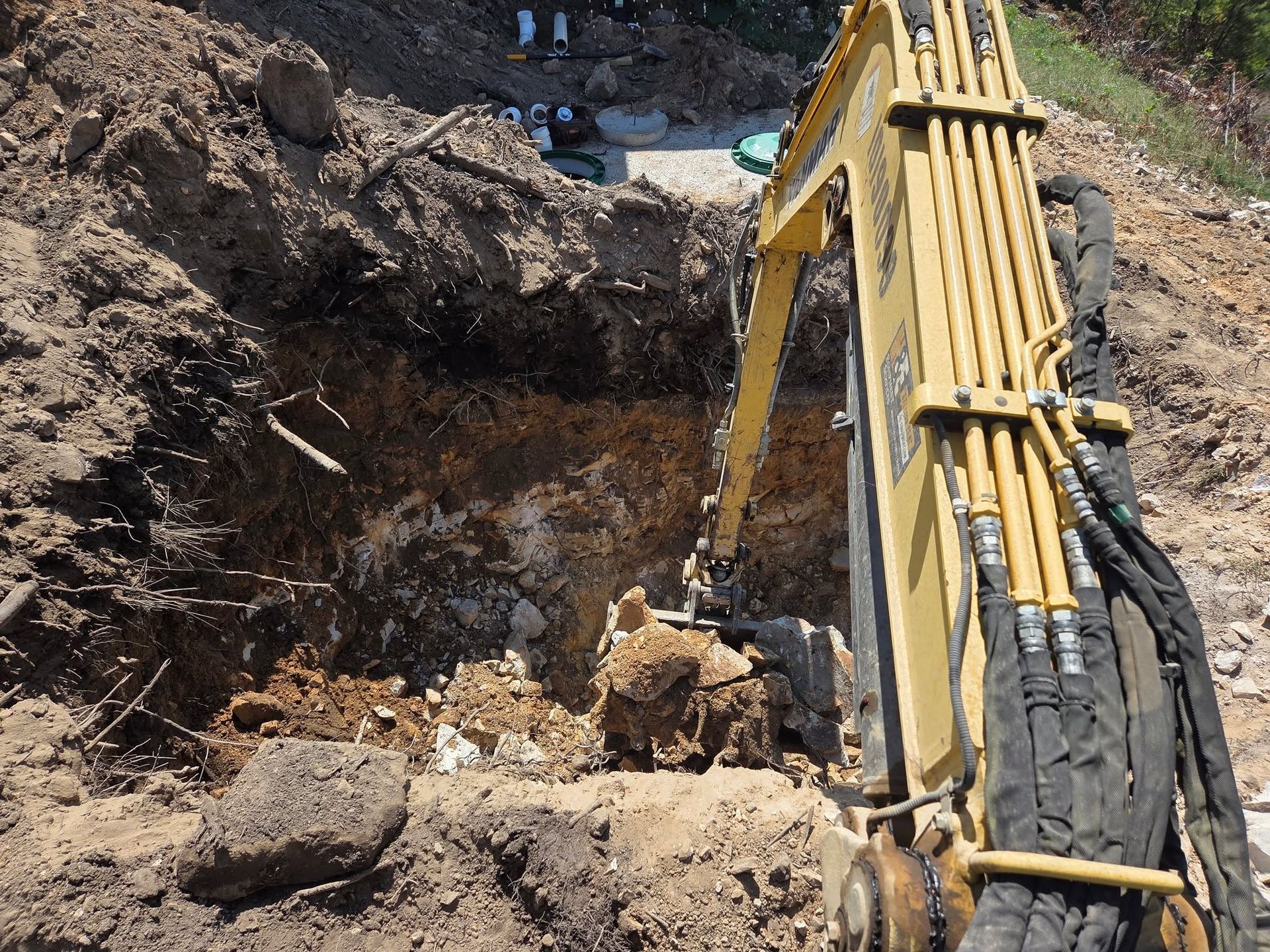 Excavator digging a muddy pit with exposed water and dirt piles at a construction site