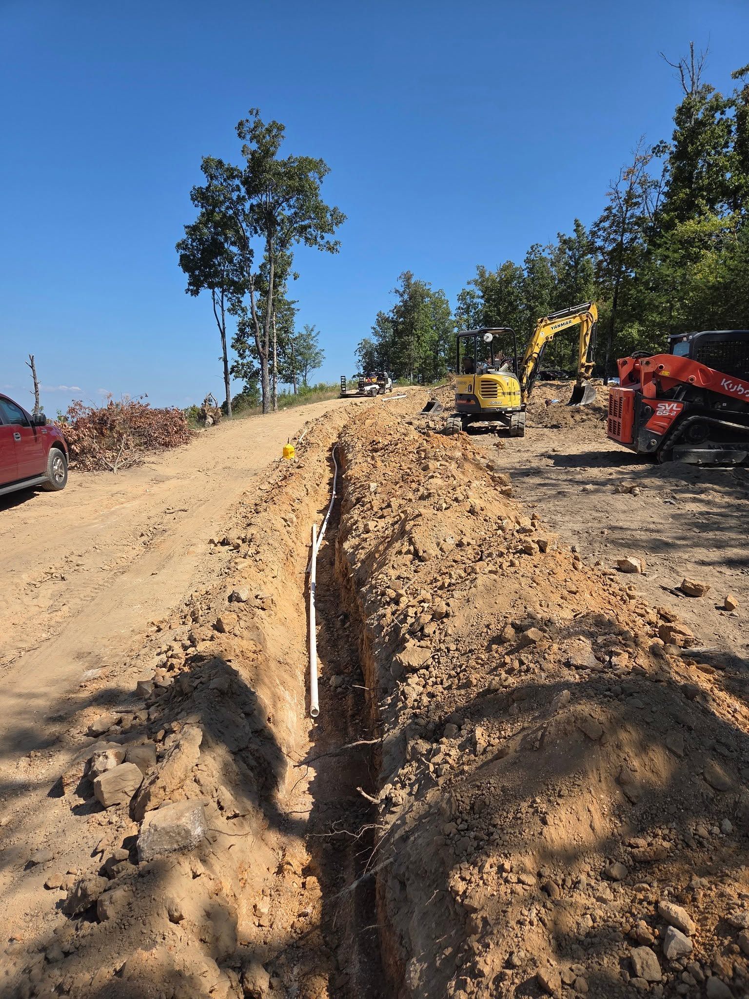 Dirt road under construction with heavy equipment and a clear blue sky