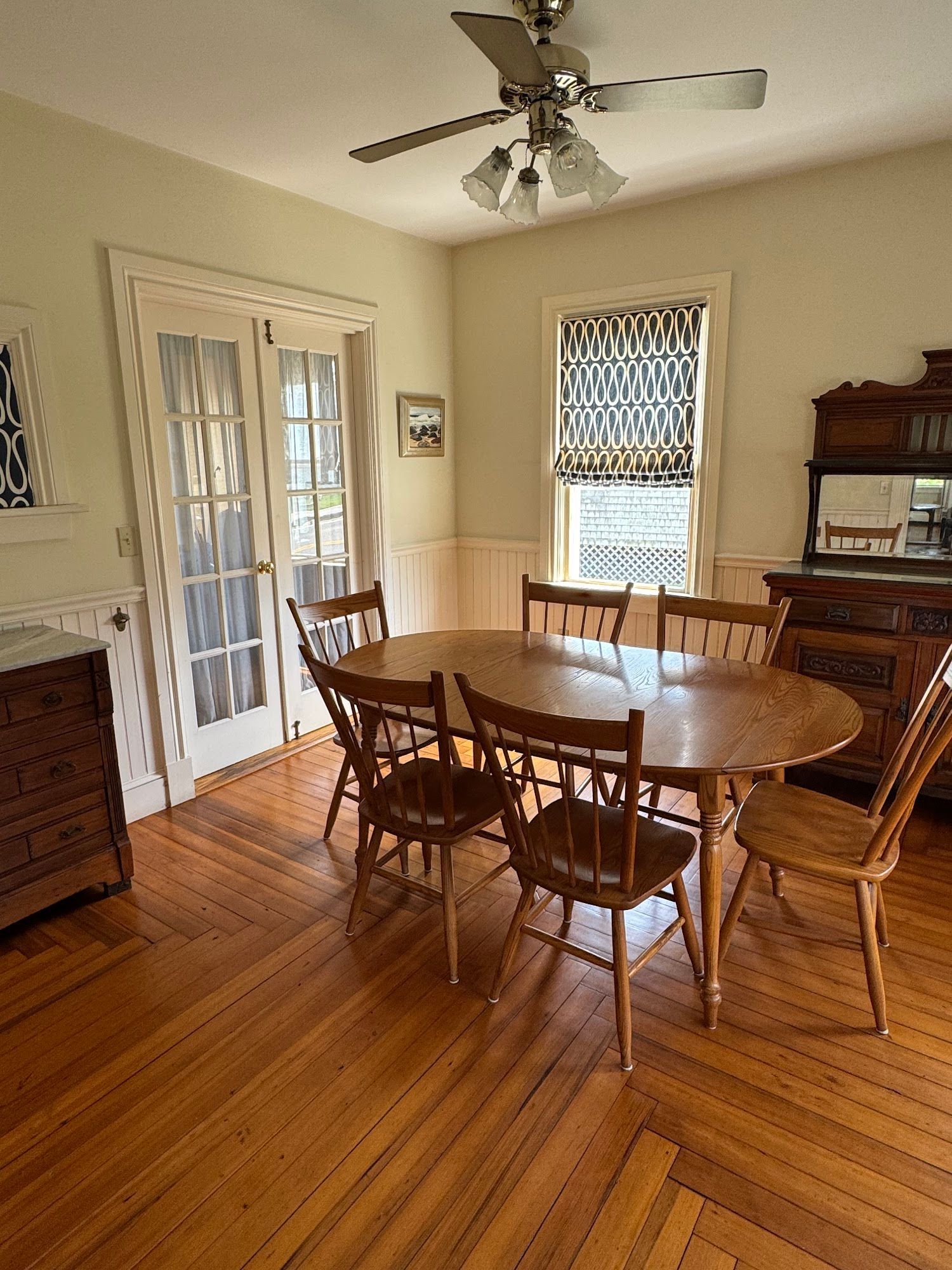 A dining room with a table and chairs and a ceiling fan.