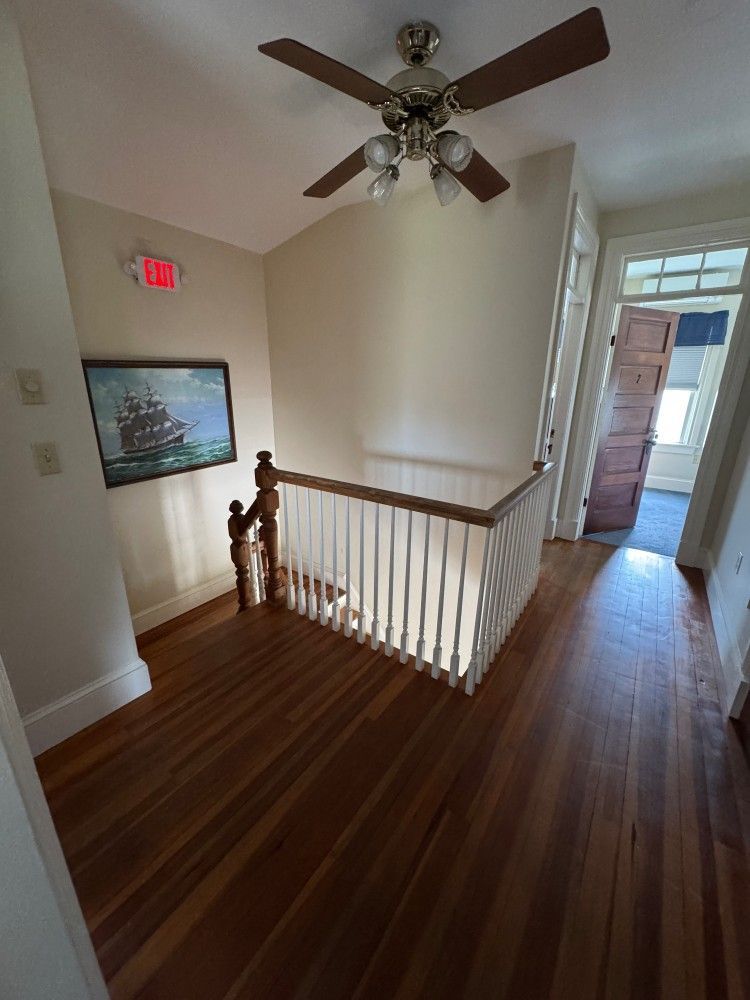 A hallway with a ceiling fan and a picture on the wall.