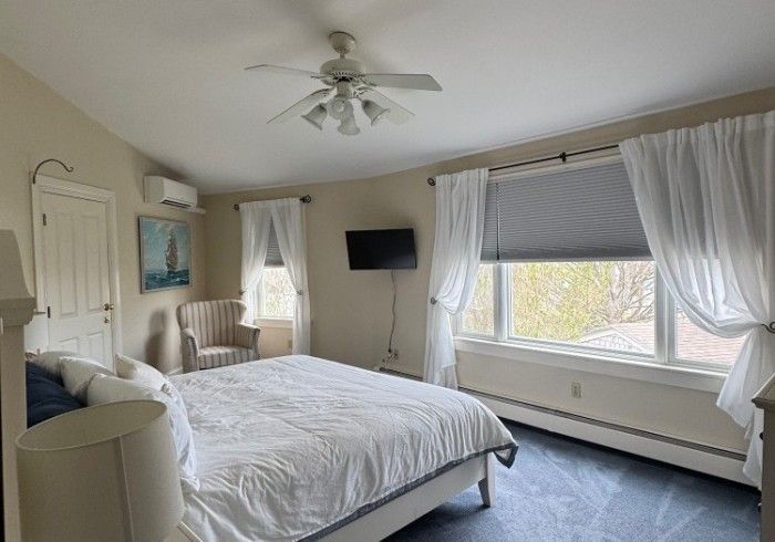 A bedroom with a bed , chair , television and ceiling fan.