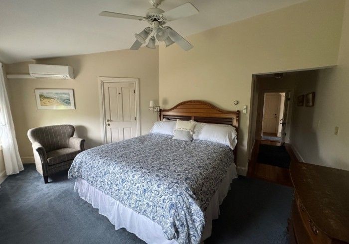 A bedroom with a king size bed a chair and a ceiling fan