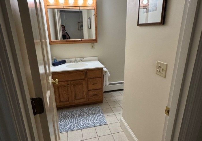 A bathroom with a sink , mirror , and cabinets.