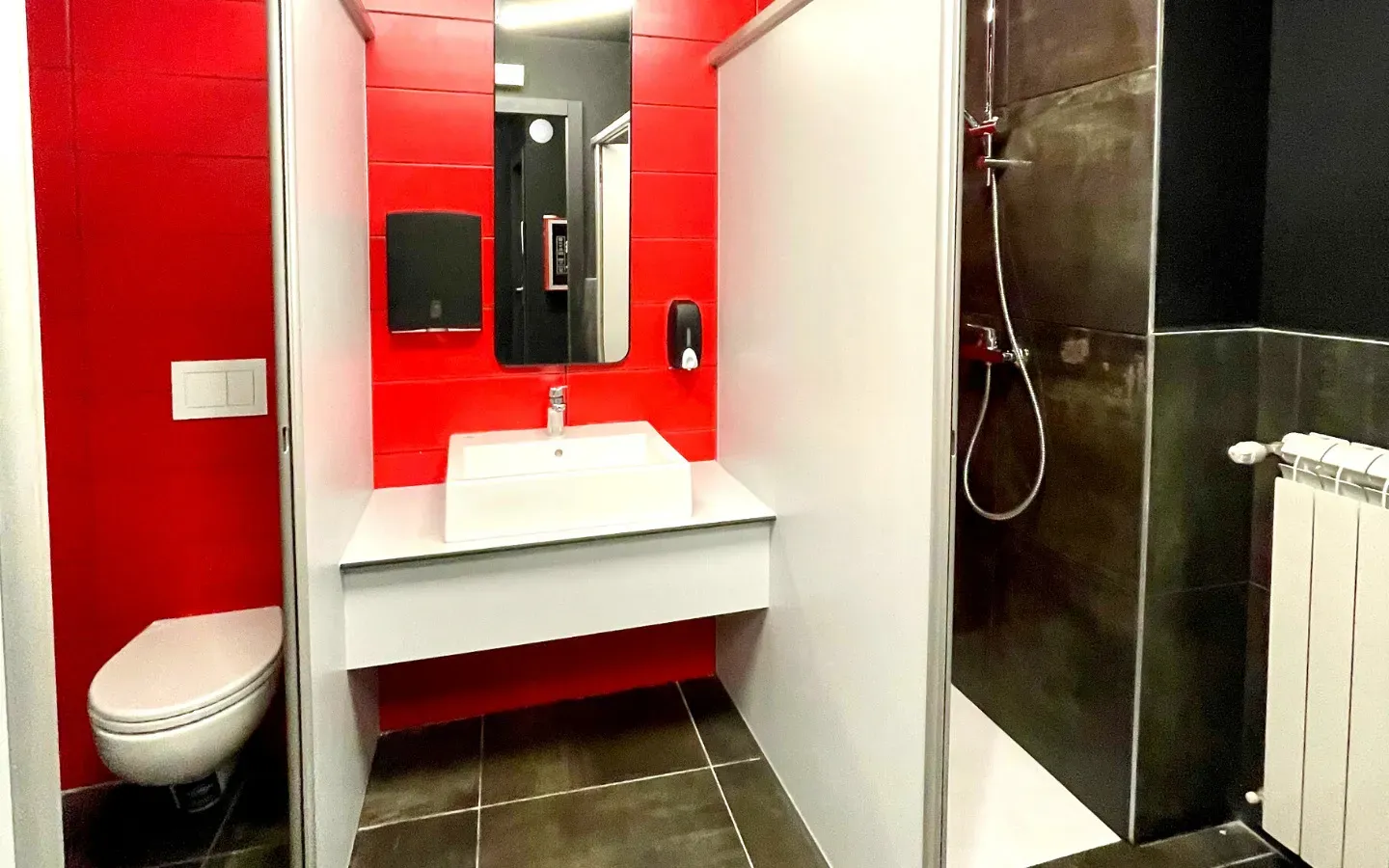 Un bagno rosso e bianco con WC, lavandino e box doccia.