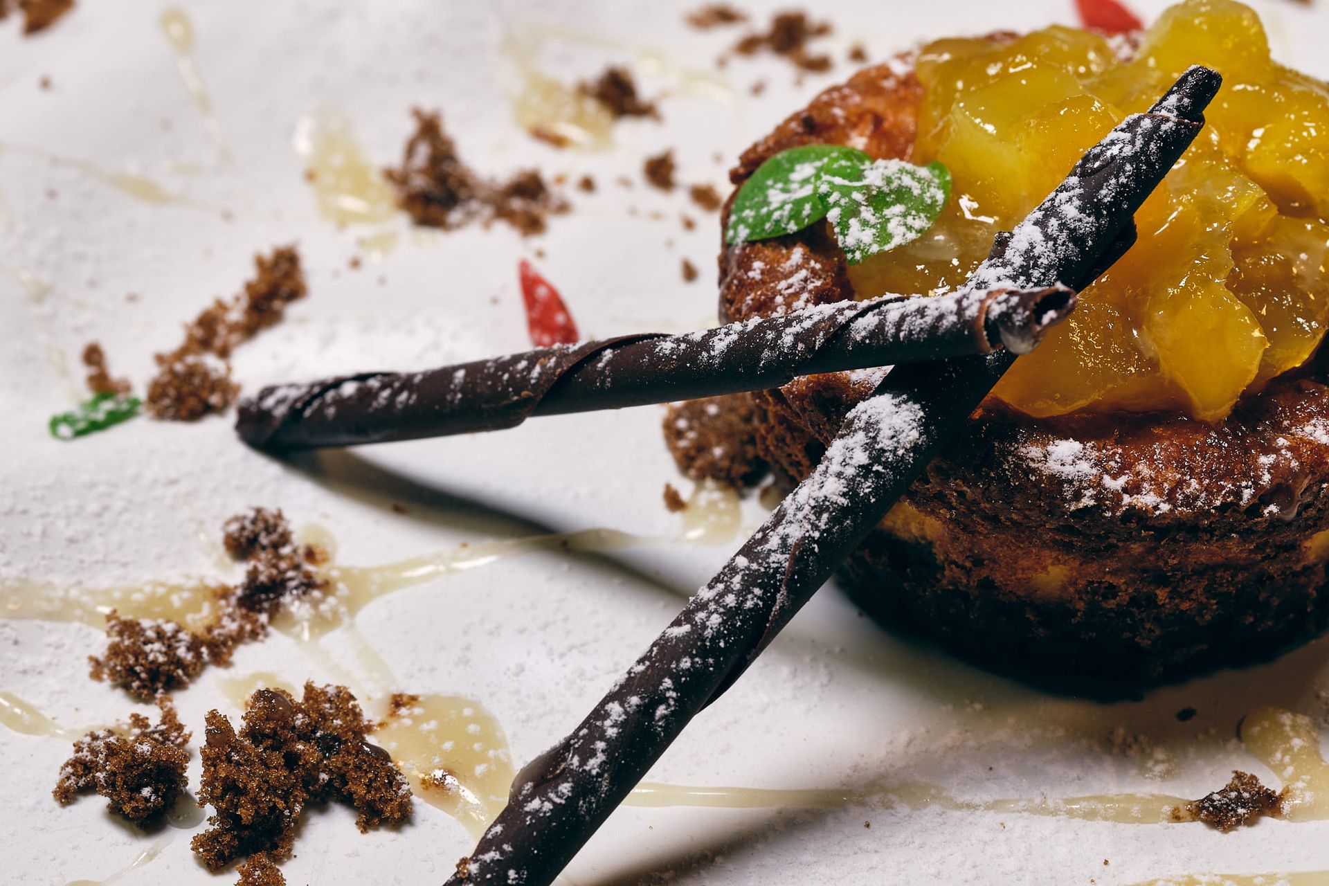 Dessert: Torta guarnita con frutta, bastoncini di cioccolato e zucchero a velo.