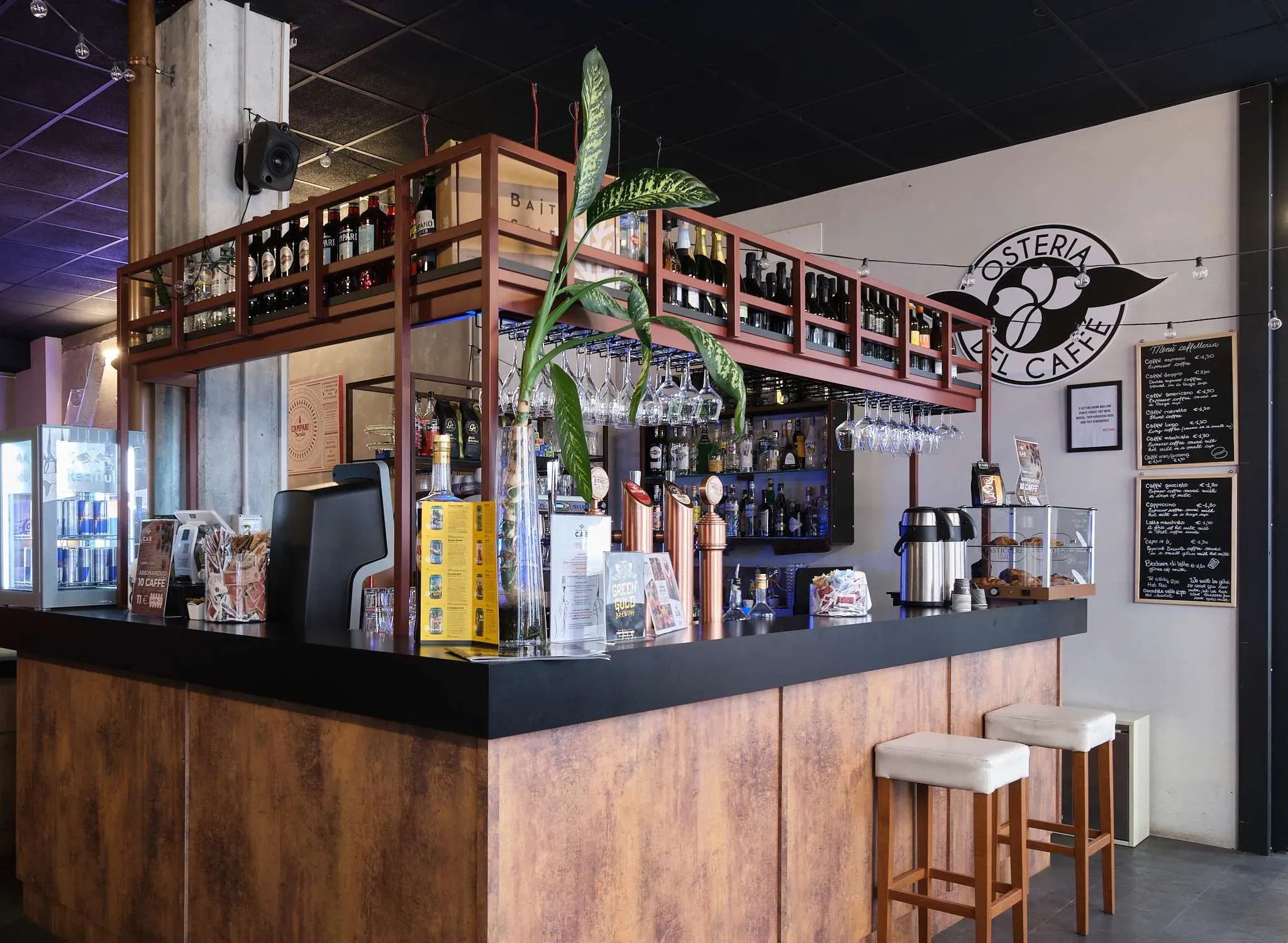Bar counter with drinks, stools, and decorative shelves.