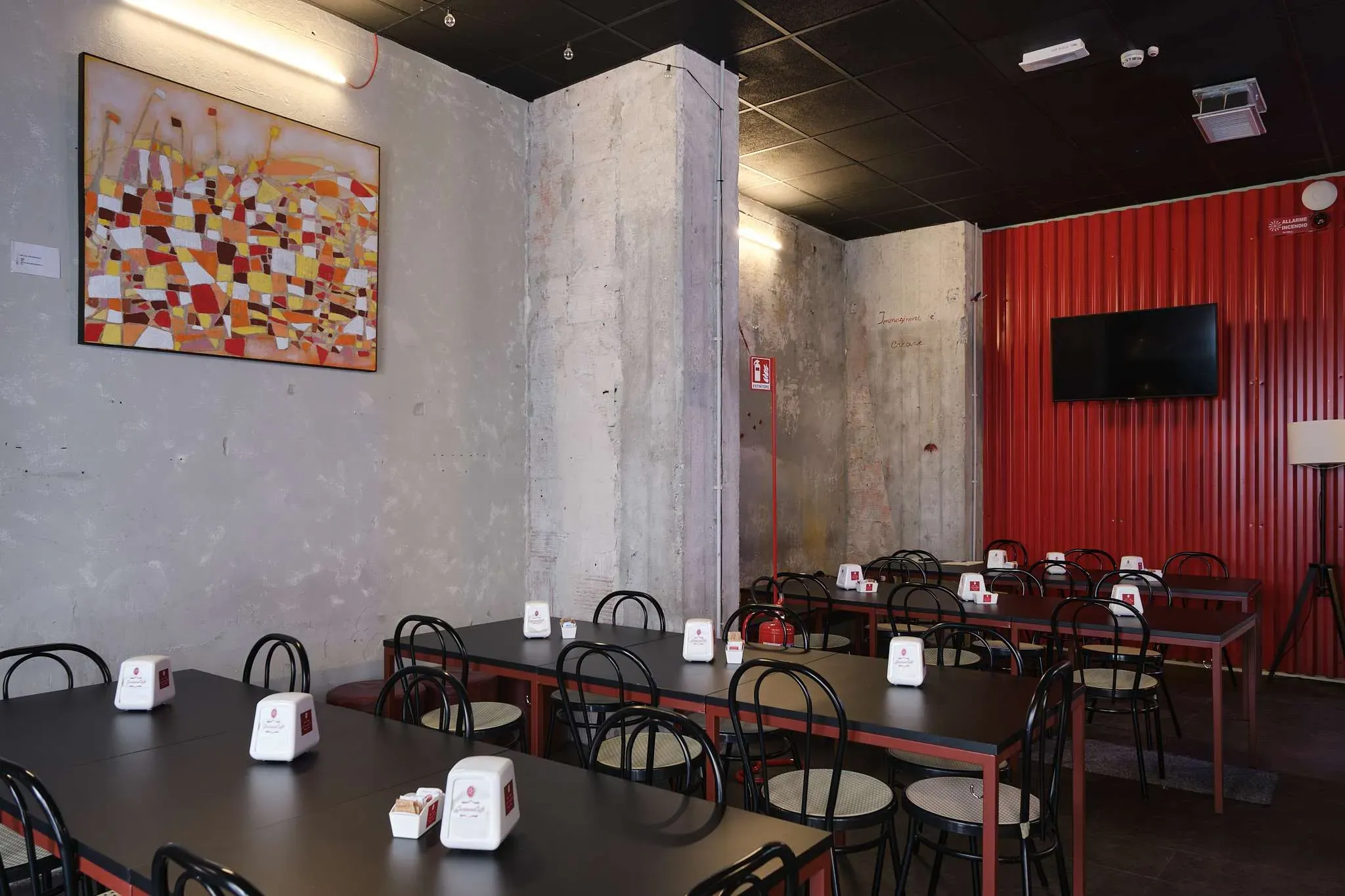 Interior of a restaurant with tables, chairs, and a large red corrugated wall.