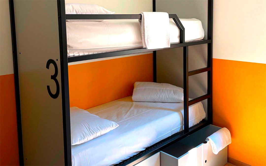 Letti a castello in una stanza di ostello, con pareti arancioni e bianche e un 