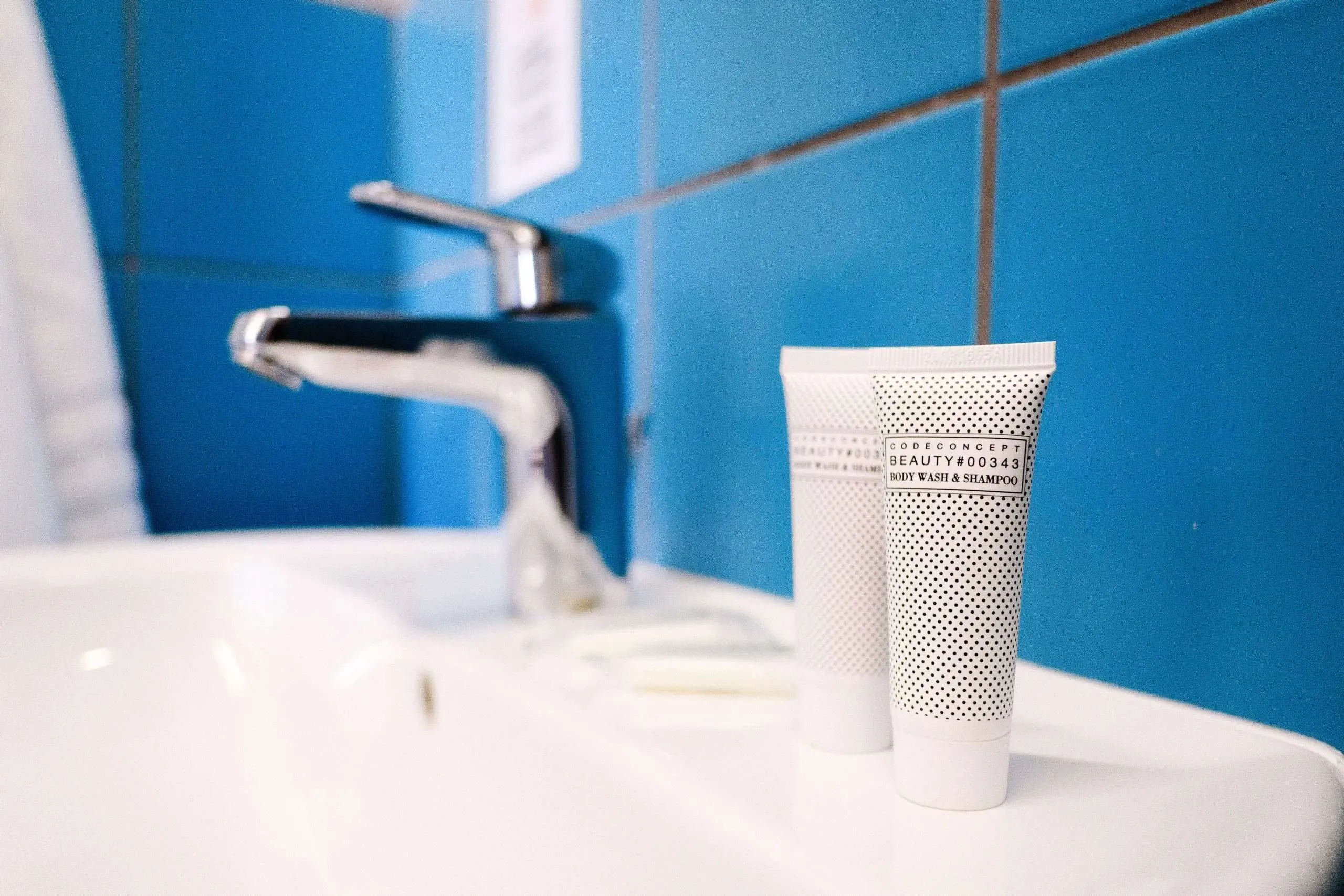 Lavandino con rubinetto cromato, articoli da toeletta e parete piastrellata blu.