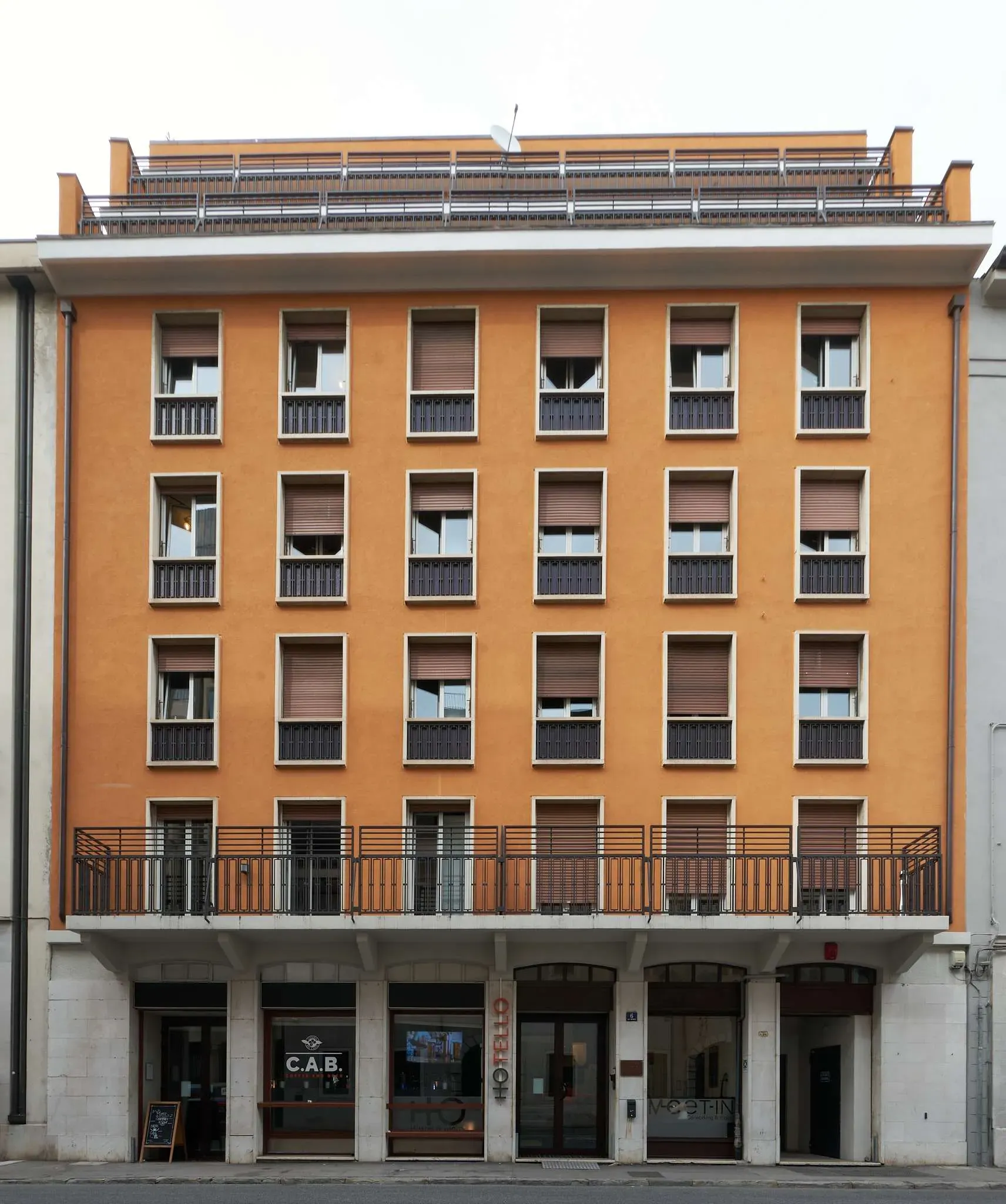 Edificio residenziale arancione con file di finestre e negozi al piano terra.