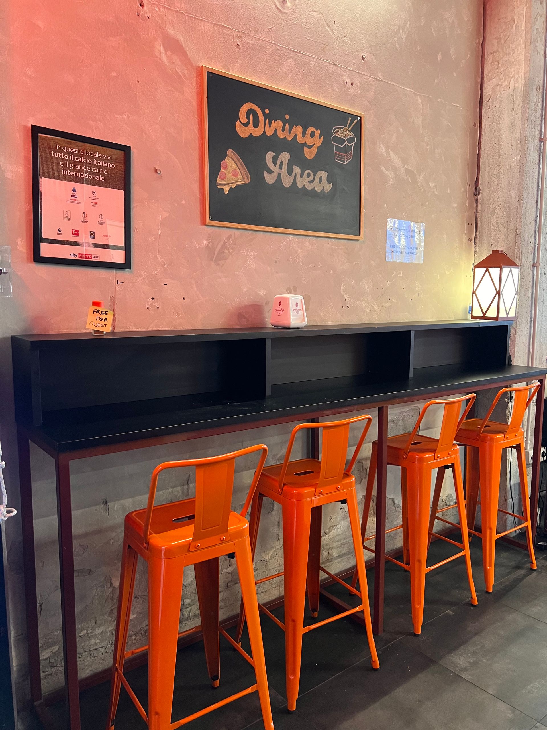 Sgabelli da bar arancioni su un bancone nella sala da pranzo. Un cartello nero indica