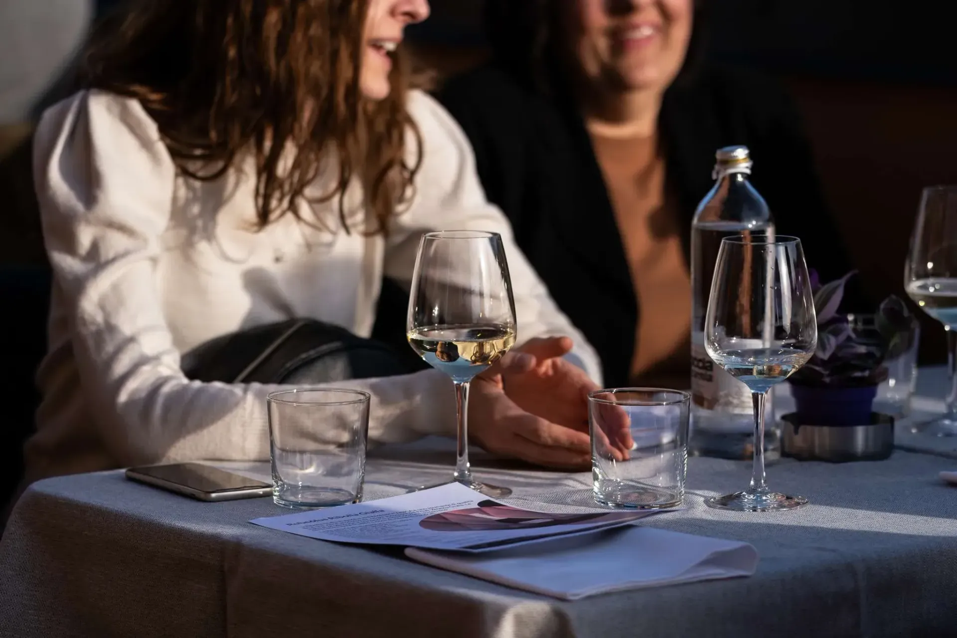 Persone che sorridono al tavolo di un bar dove stanno bevendo vino