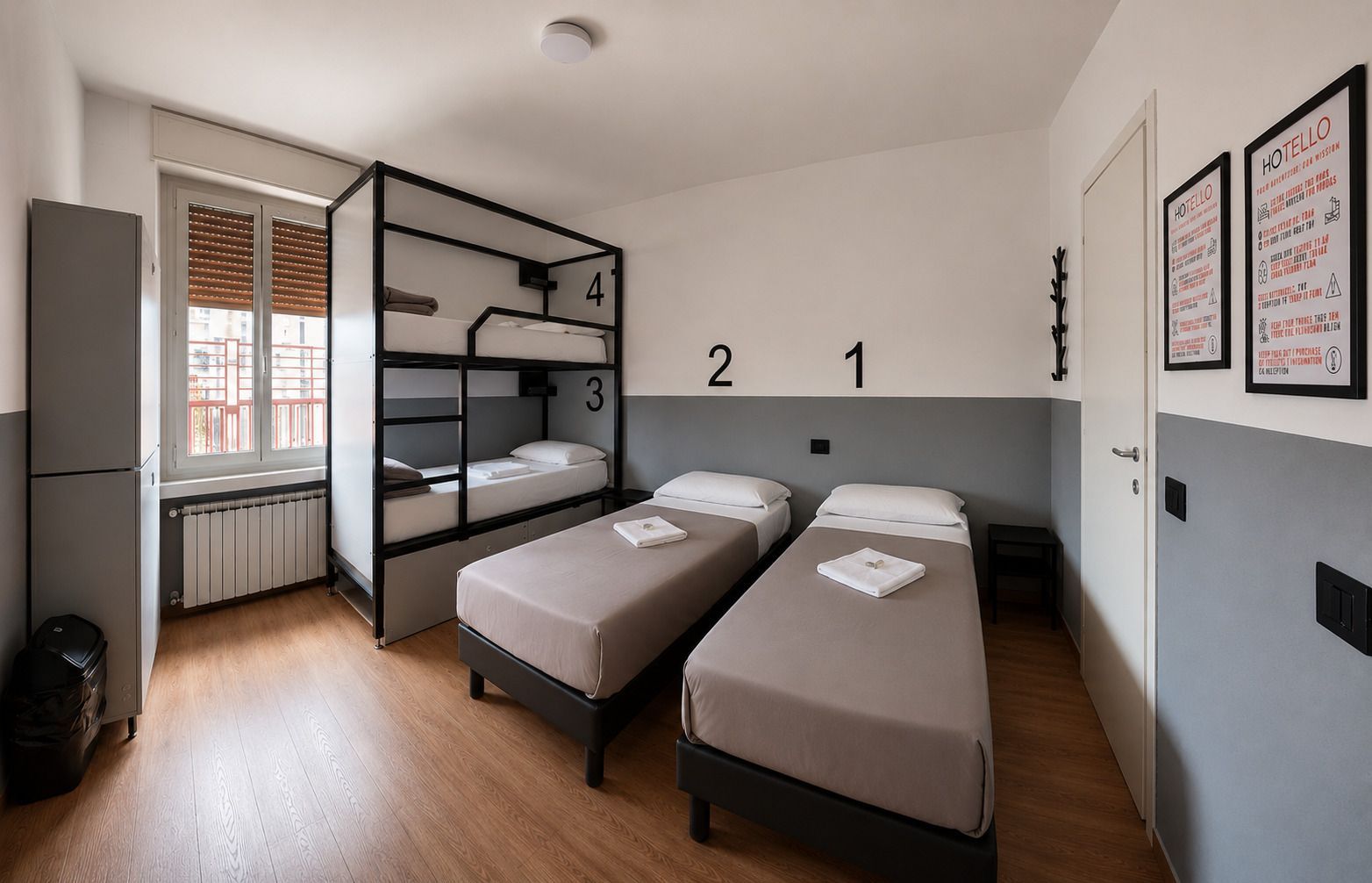 Una stanza del dormitorio con letti a castello, due letti singoli, pareti grigie e bianche e una finestra.