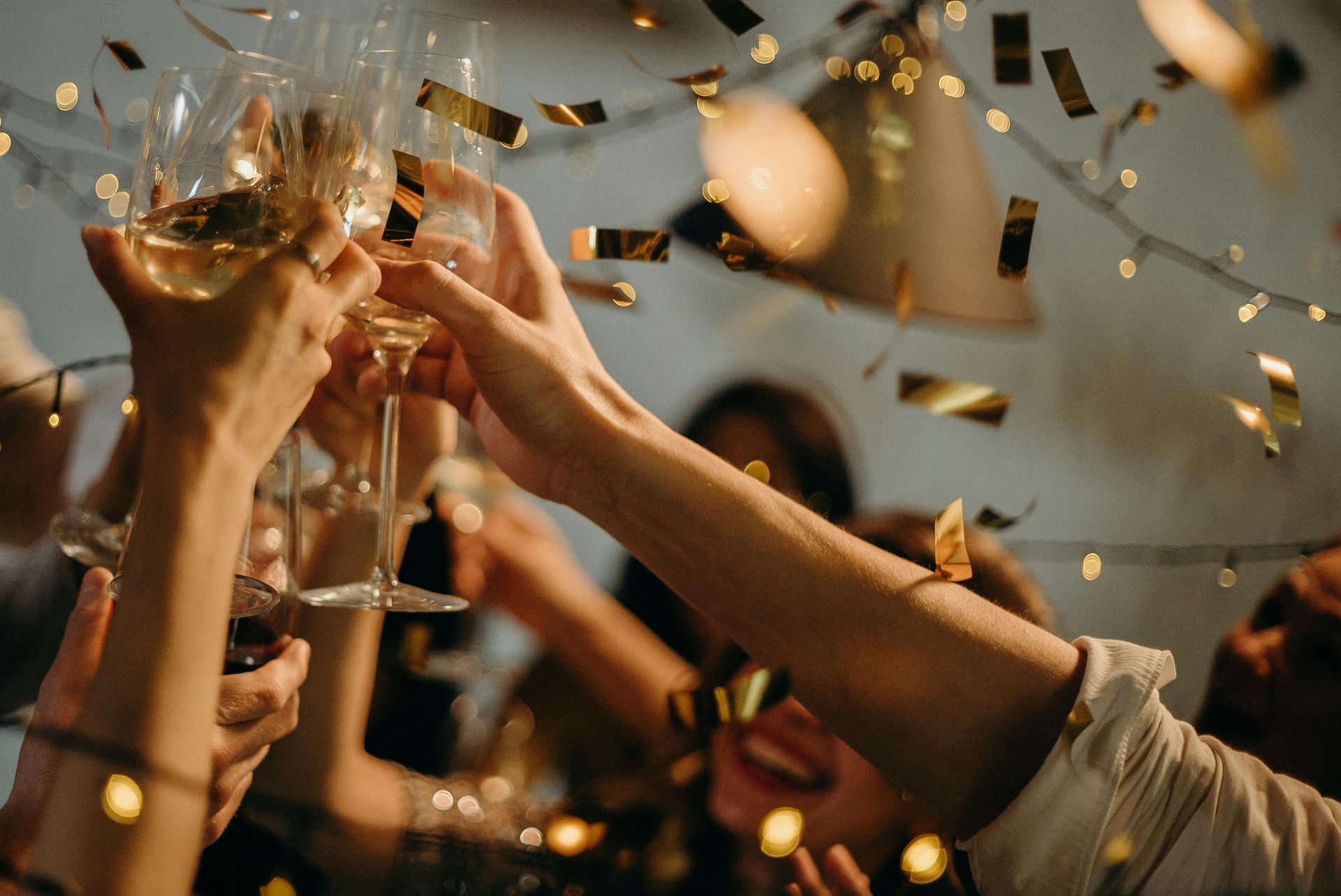 Persone che brindano con calici di champagne, coriandoli che cadono, festeggiano.