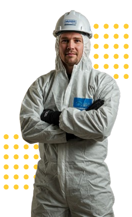 Construction worker in white protective suit and helmet, arms crossed, smiling.