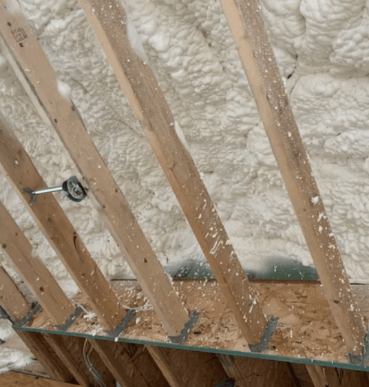 Attic with spray foam insulation between wooden rafters.