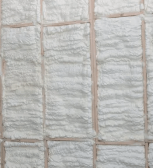 White spray foam insulation fills wooden wall framing.