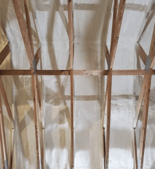 Wooden rafters with tan spray foam insulation.