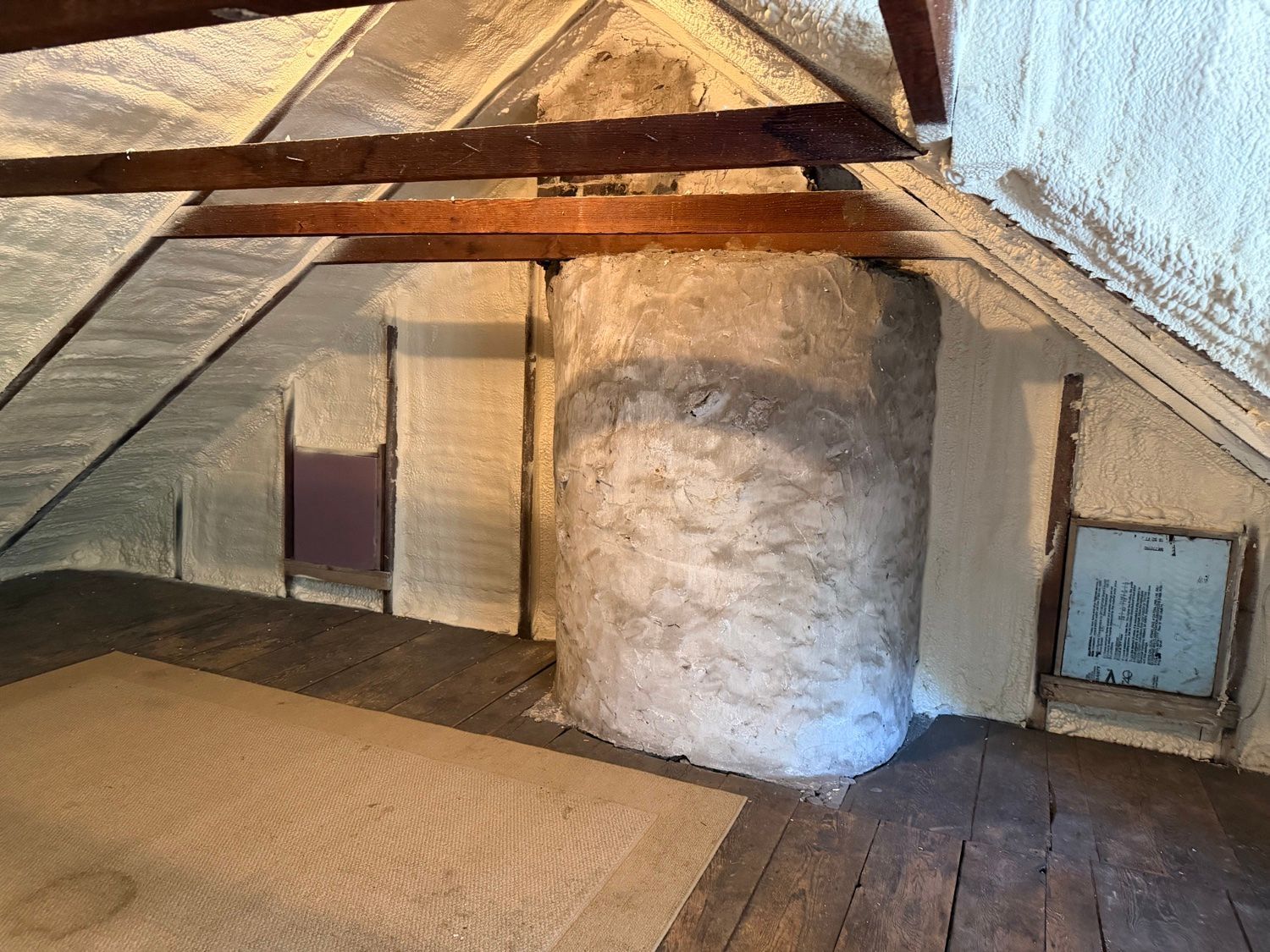 Attic spray foam insulation around a stone chimney in an older home, Pennsylvania