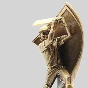 Cricket player in helmet swings a bat with a large shield on his back, against a plain background