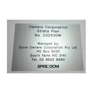 Plaque for Owners Corporation Strata Plan No. 332430W, managed by Spire OCM, on a gray wall.