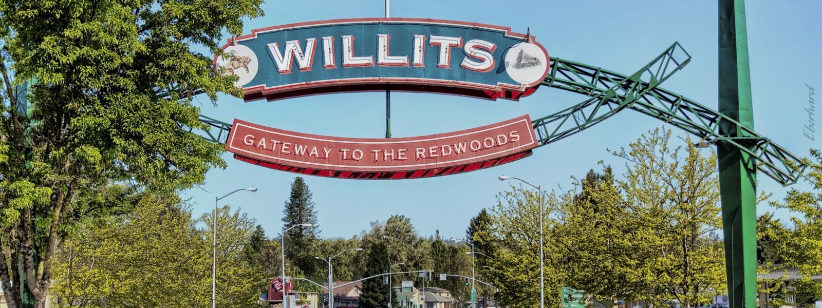 Sign for Willits, California, with the name displayed above, and a historical museum below. Green framing.