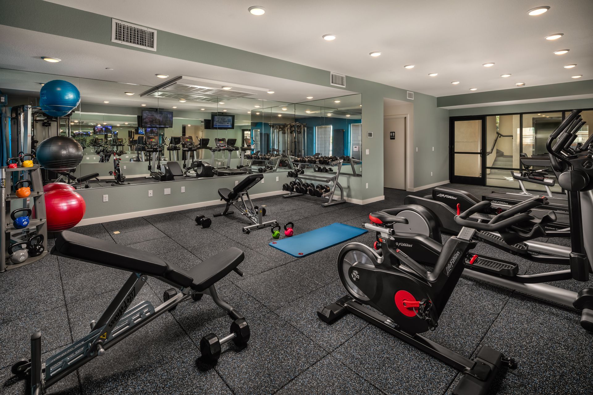 A gym with a lot of exercise equipment and a large mirror.