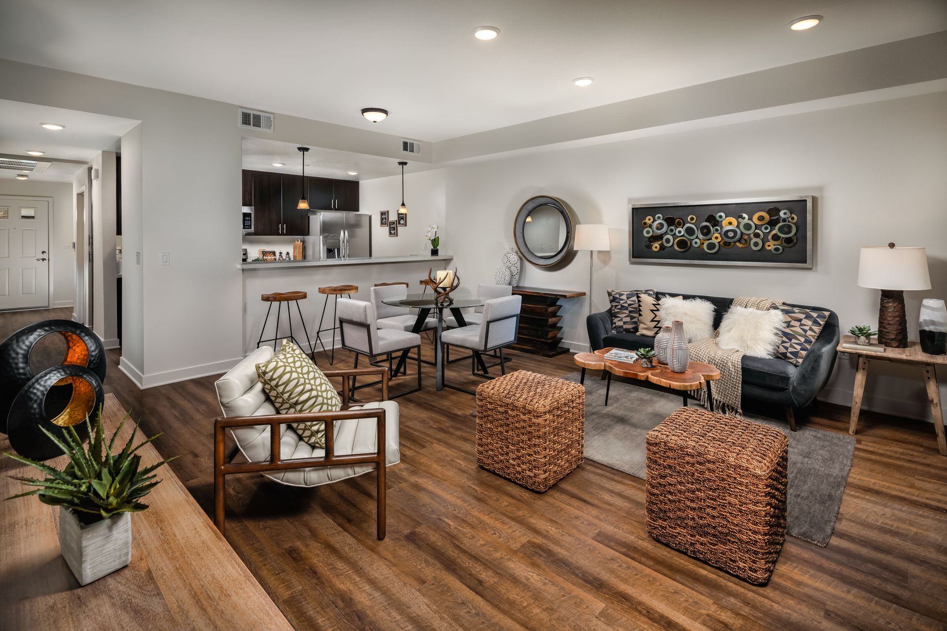 A living room with a couch , chairs , ottomans and a table.
