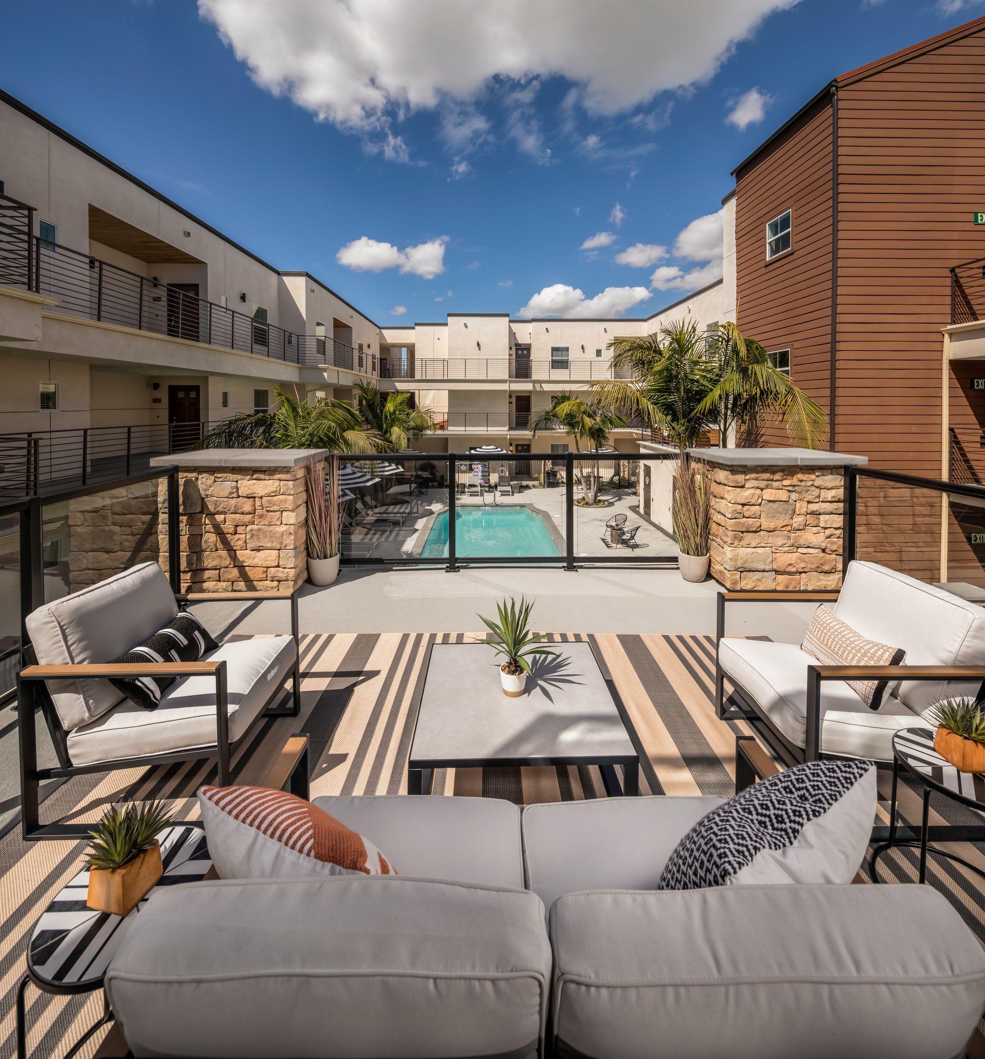 A patio with a couch and chairs and a pool in the background