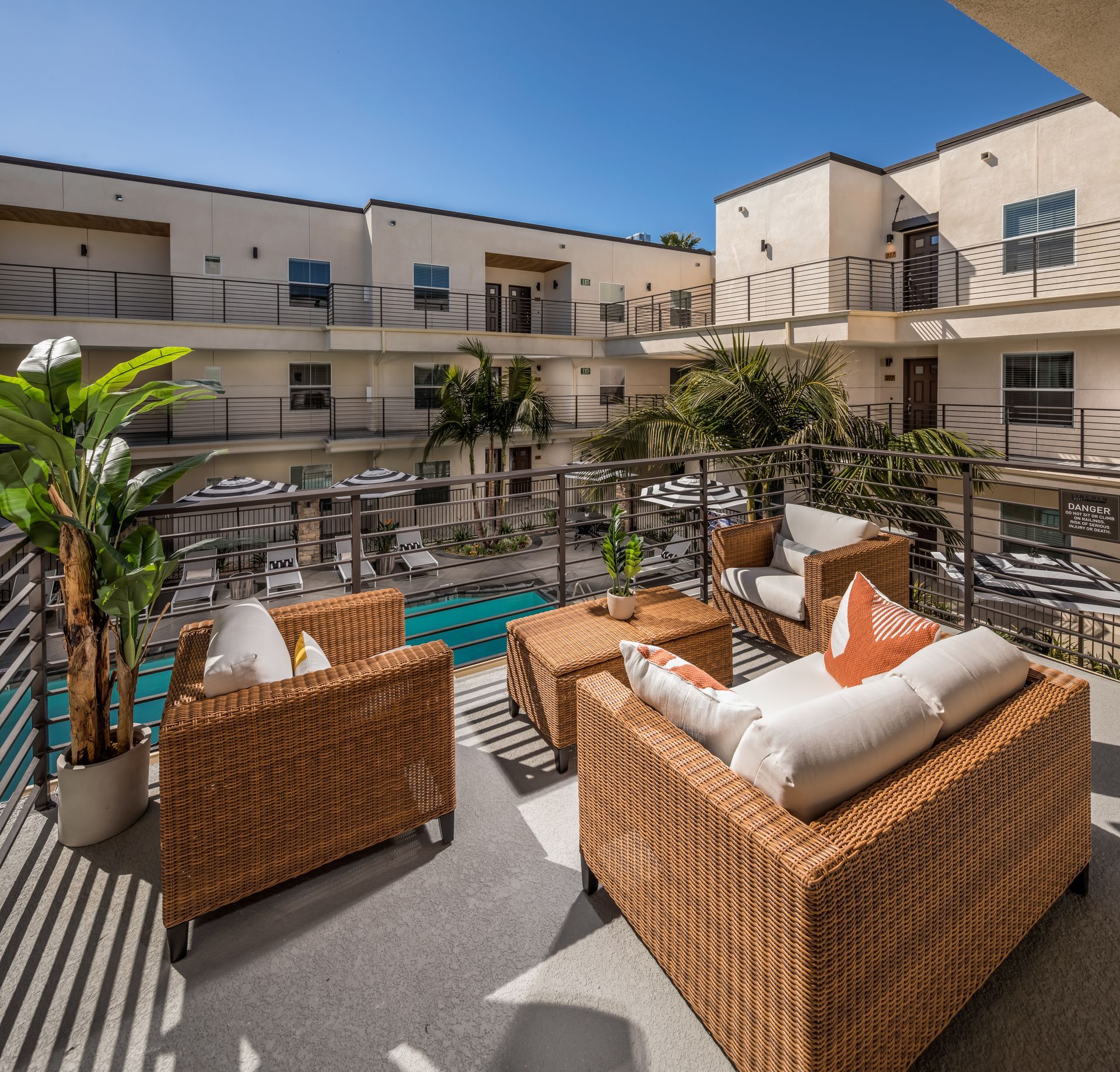 A balcony with wicker furniture and a pool in the background