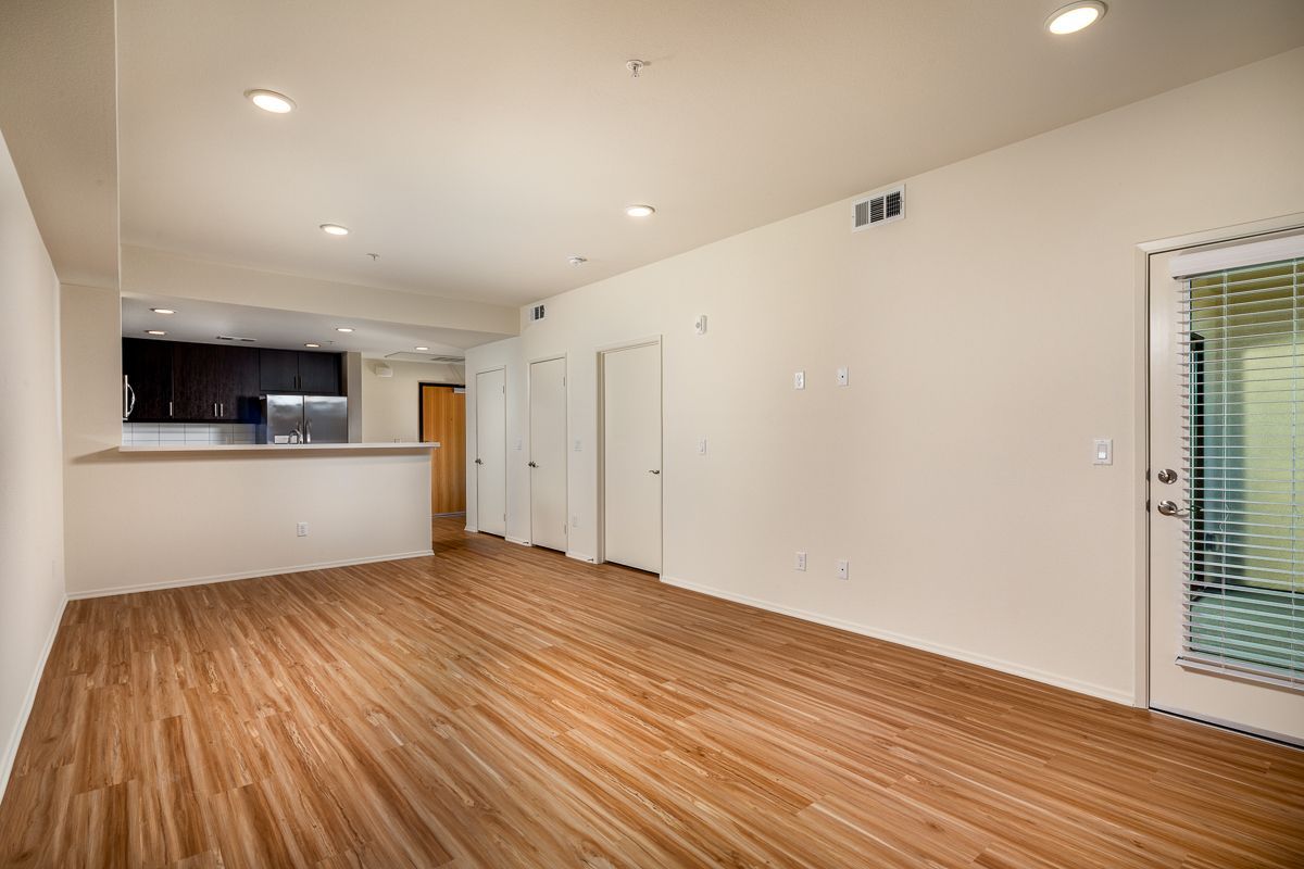 An empty living room with hardwood floors and white walls.