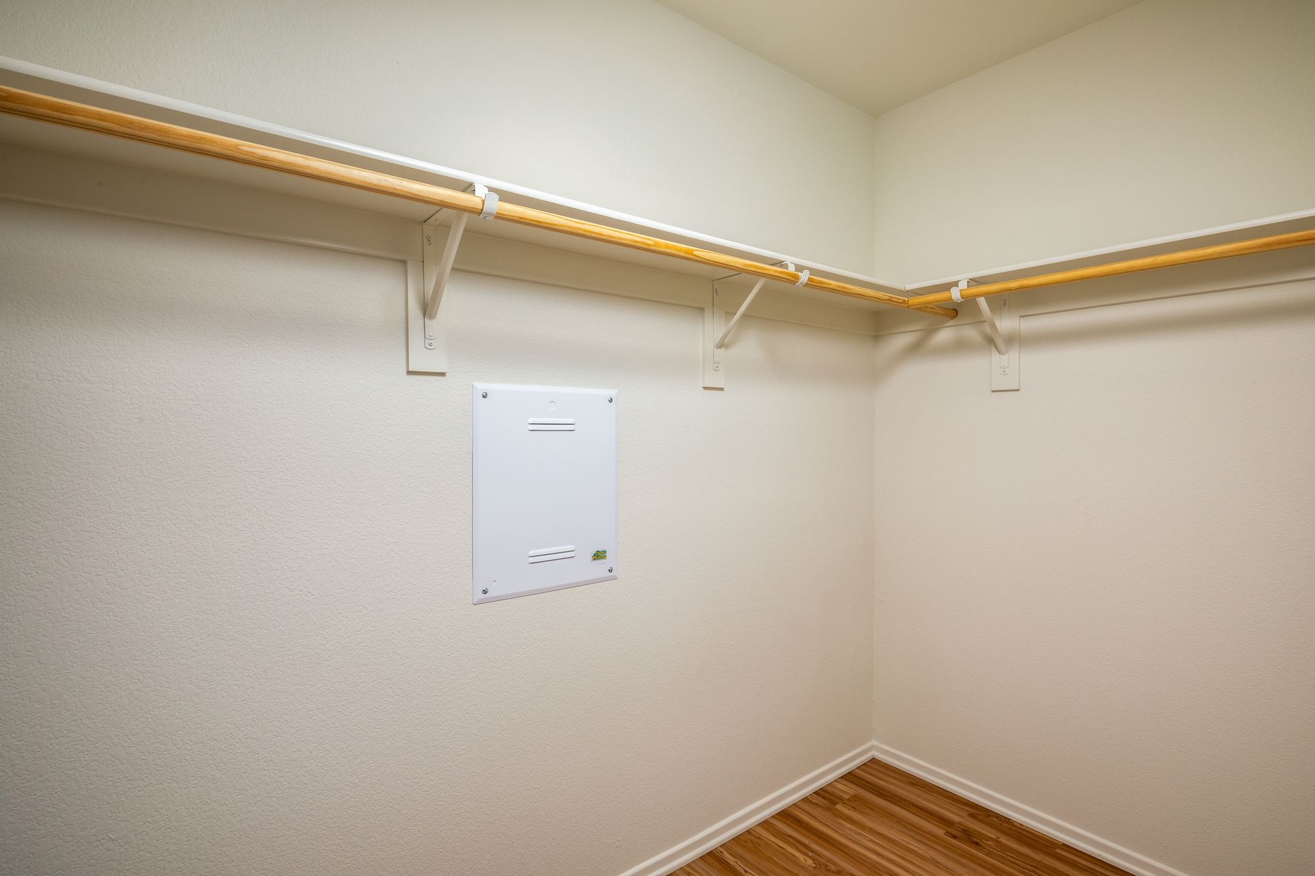 An empty walk in closet with wooden floors and shelves.