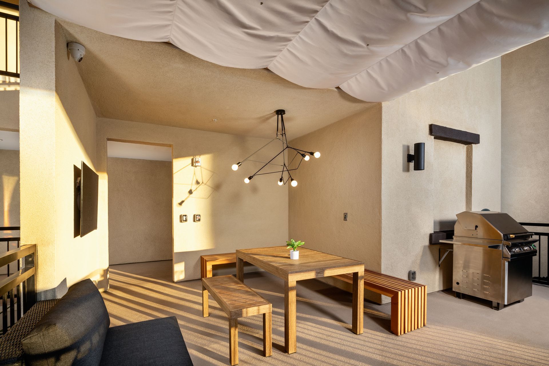 A living room with a table and benches and a grill