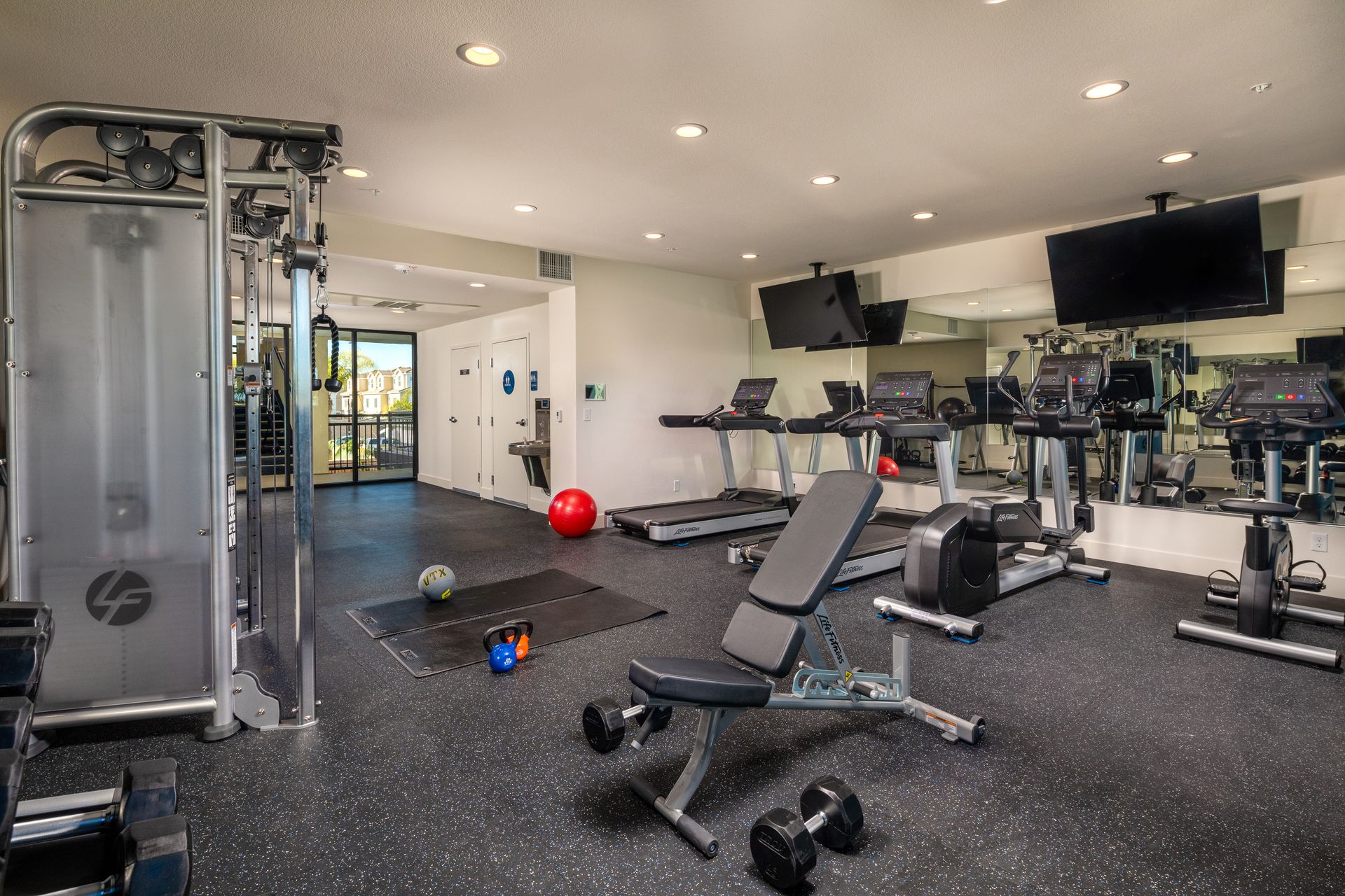 A large gym with a lot of equipment and a bench.