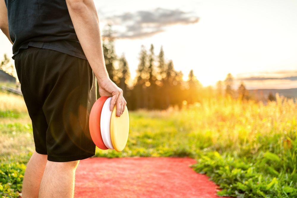A man is holding two frisbees in his hands in a field.