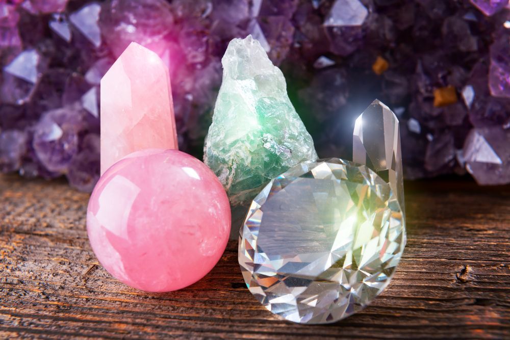 Three different types of crystals are sitting on a wooden table.