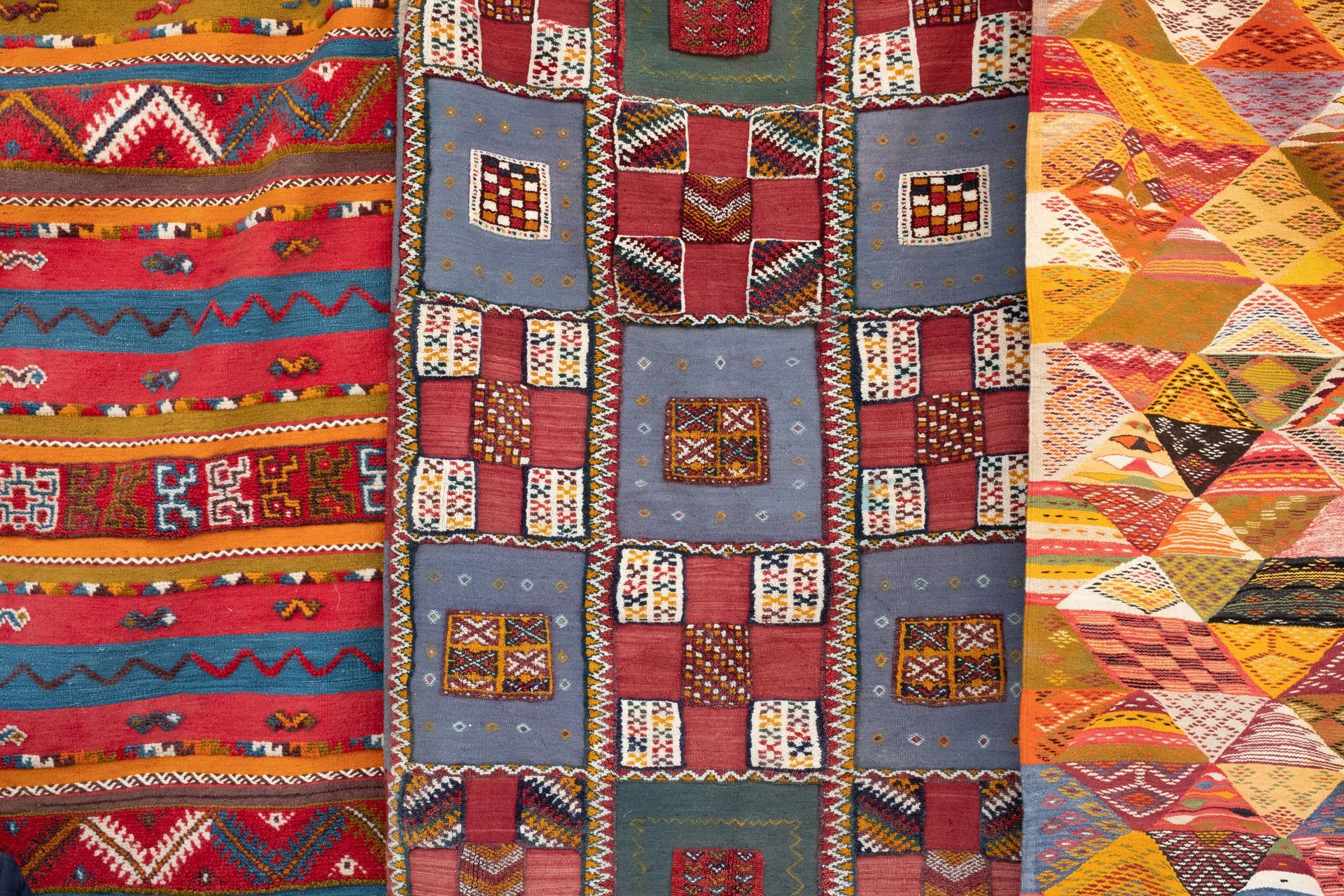 Colorful patchwork textiles with geometric patterns in red, blue, orange, and yellow.