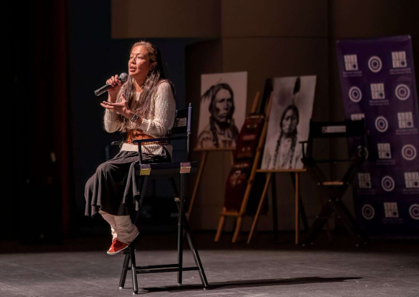 A woman is sitting in a chair holding a microphone.
