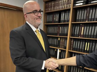 Two people shaking hands in a library with bookshelves in the background.