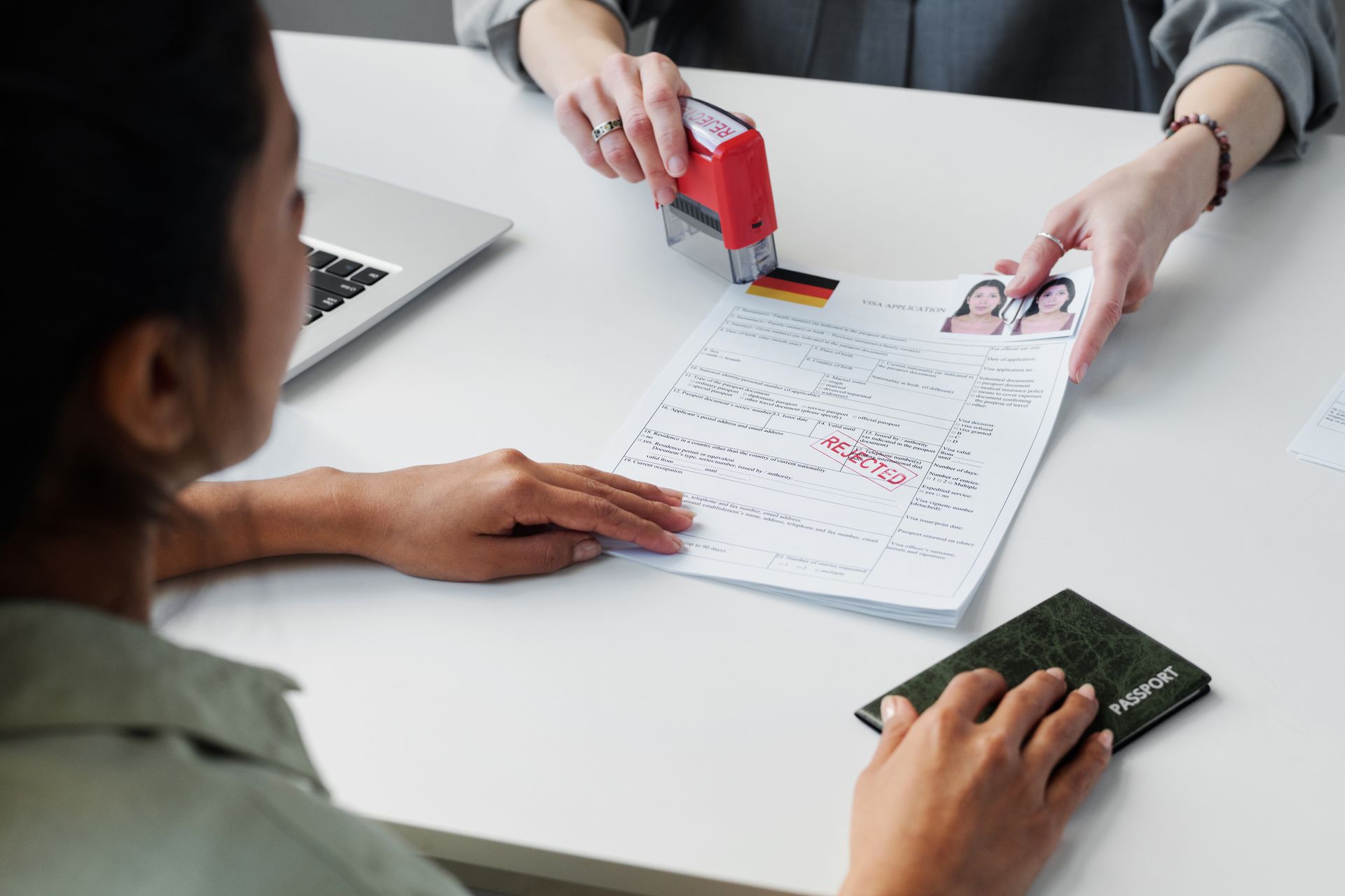 Hands reviewing a passport and stamped application form across a white desk at an office counter