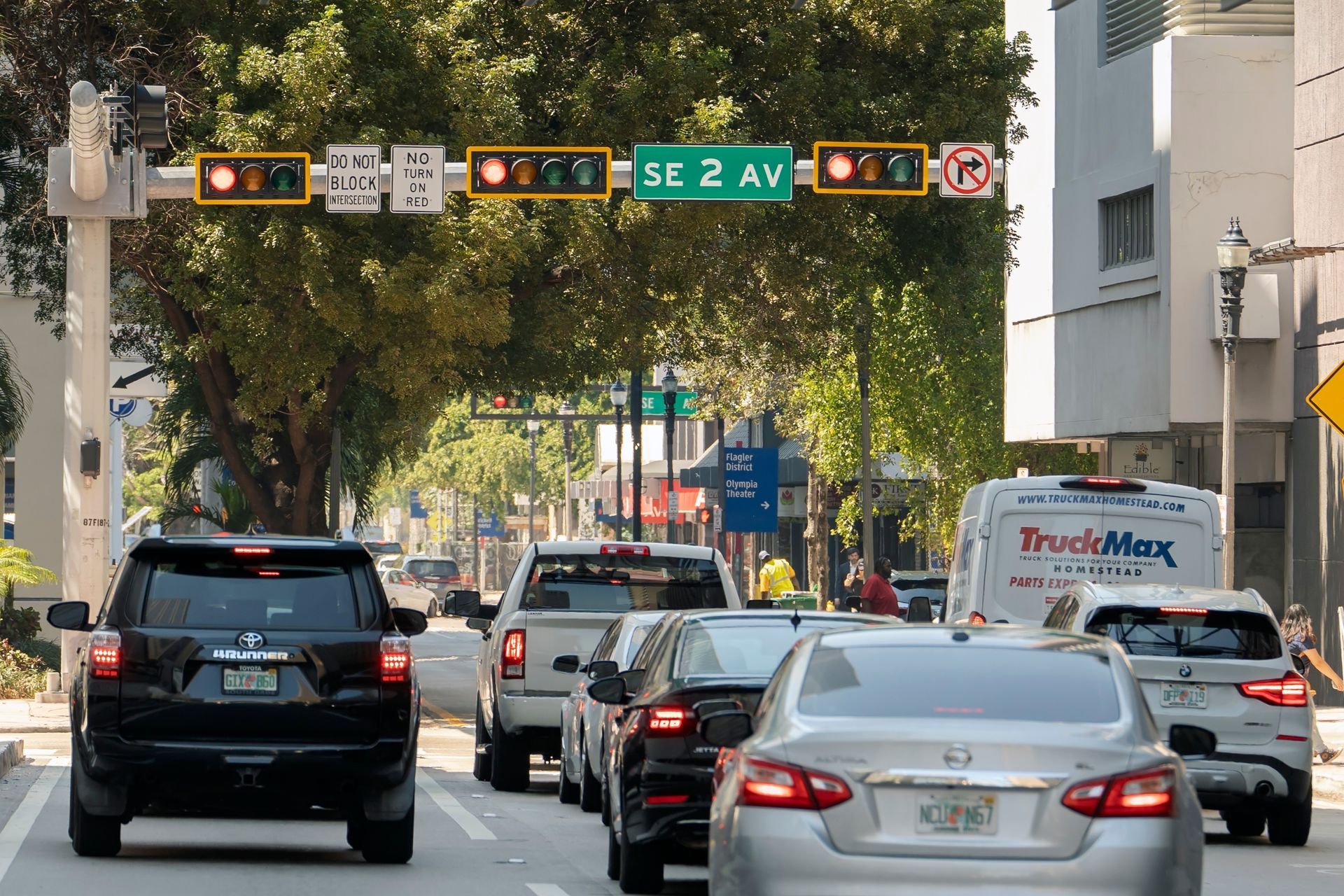 Cars stopped at a city intersection under traffic lights and a street sign reading “12 Av.”
