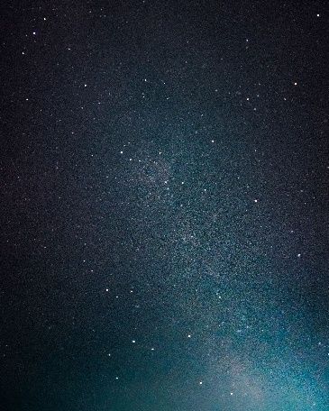 Starry night sky with a faint Milky Way band and a soft blue glow near the horizon