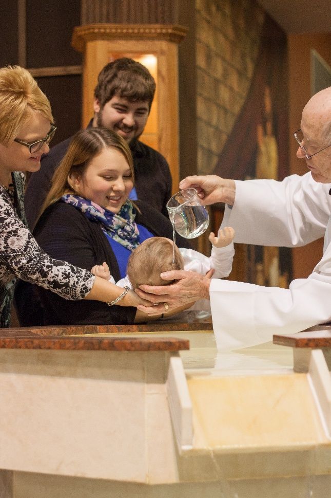 Priest pouring water over a personโs head during a baptism ceremony