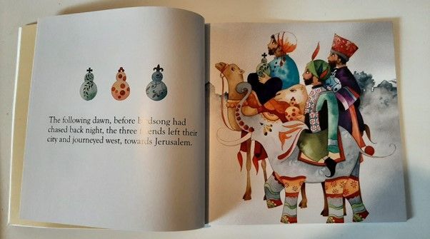 A book is open to a page showing three wise men on camels