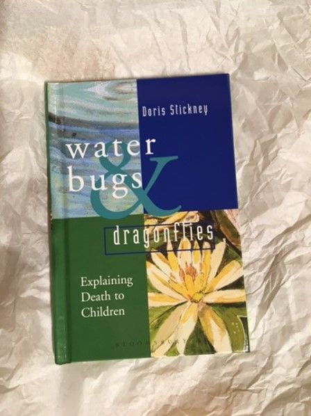 A book titled water bugs and dragonflies is laying on a white cloth
