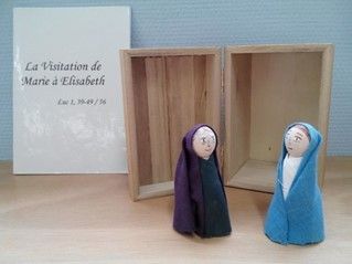 Two dolls are sitting next to each other on a wooden table.