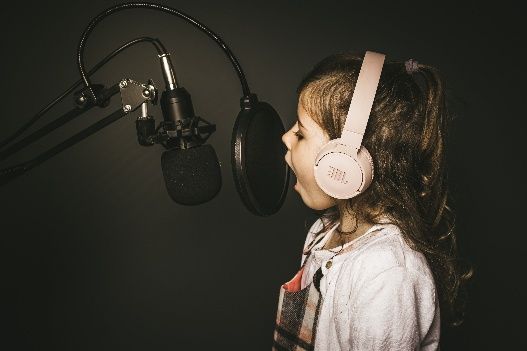 Child wearing headphones singing into a microphone in a recording studio