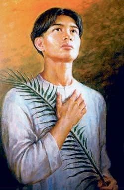 Portrait of a person in a white shirt holding a palm frond across the chest against a warm brown background