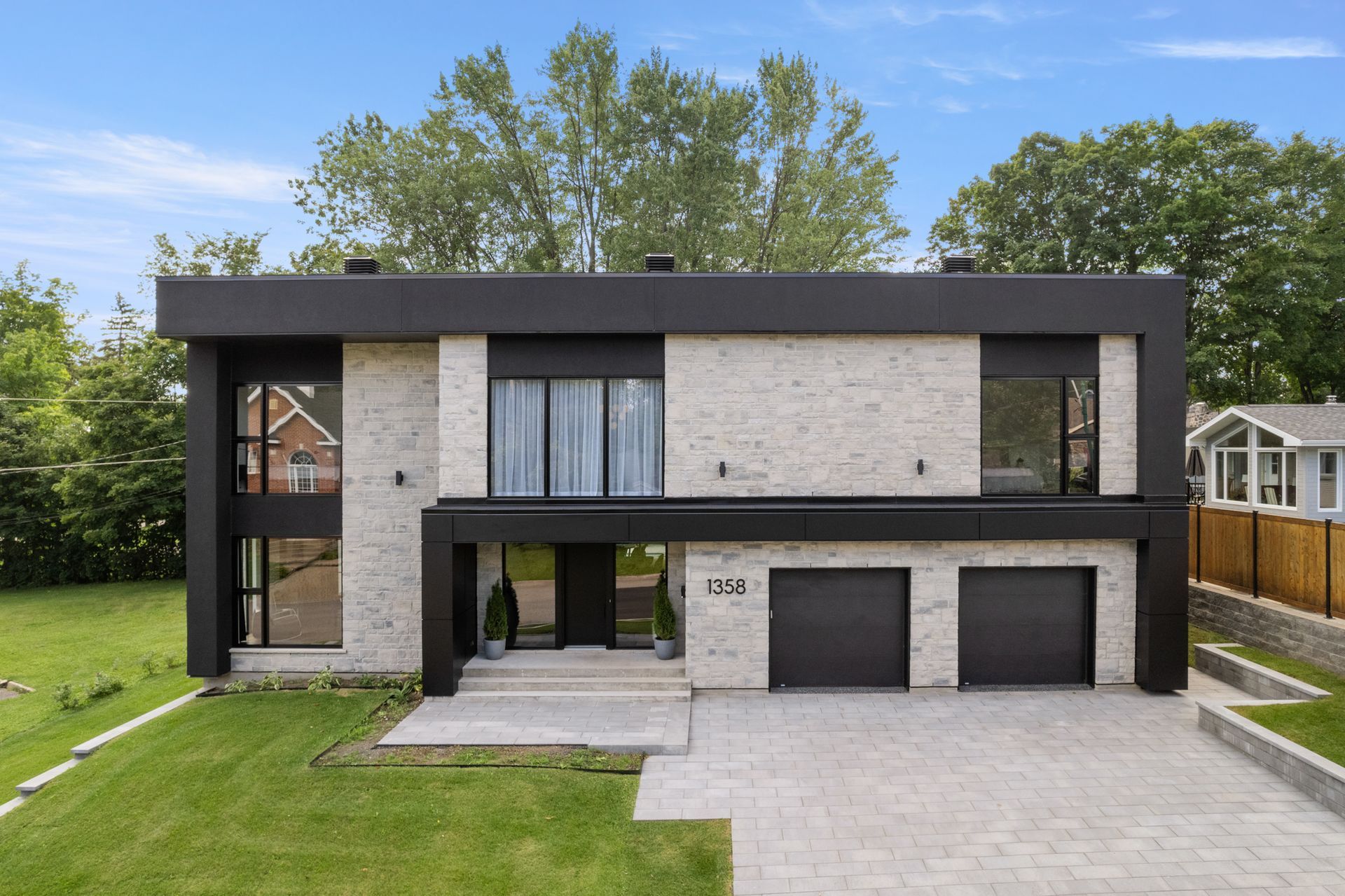 Une maison moderne avec deux garages et une grande pelouse devant.